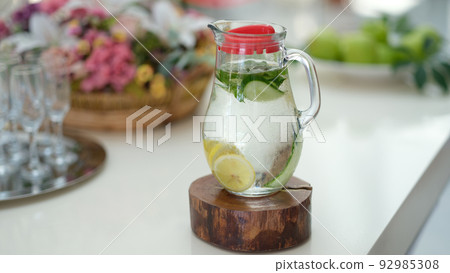 Infused detox water with cucumber, lemon and mint in jug on table Infused detox water with cucumber, lemon and mint in jug on table 92985308