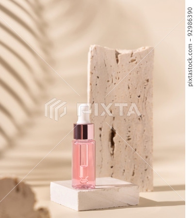 Dropper Bottle on travertine stone and palm leaf shadow on light yellow 92986390