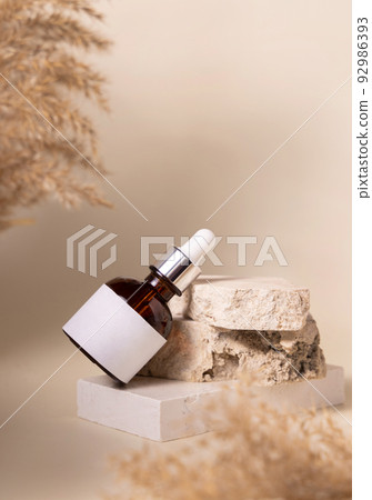 Brown dropper cosmetic bottle with blank label on stone near pampas grass, Mockup Brown dropper cosmetic bottle with blank label on stone near pampas grass, Mockup 92986393