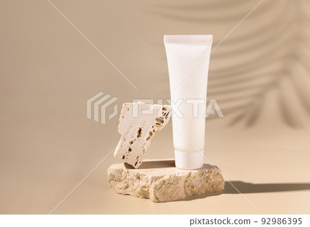 White plastic cream tube on stone on light yellow, Palm leaf hard shadows. Mockup White plastic cream tube on stone on light yellow, Palm leaf hard shadows. Mockup 92986395