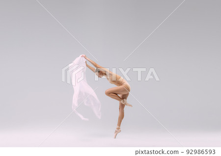Portrait of young ballerina dancing with fabric isolated over grey studio background. Graceful, tenderm weightless artist 92986593