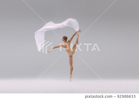 Portrait of young tender ballerina dancing in beige cloth with transparent fabric isolated over grey studio background. Looks weightless Portrait of young tender ballerina dancing in beige cloth with transparent fabric isolated over grey studio background. Looks weightless 92986633