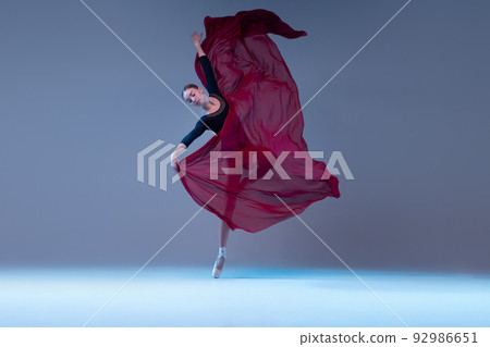 Portrait of young flexible ballerina dancing with fabric isolated over blue grey studio background. Tender deep red flower Portrait of young flexible ballerina dancing with fabric isolated over blue grey studio background. Tender deep red flower 92986651
