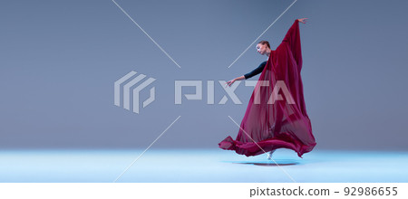 Portrait of young ballerina dancing covered with deep red transparent fabric isolated over blue grey studio background. Portrait of young ballerina dancing covered with deep red transparent fabric isolated over blue grey studio background. 92986655
