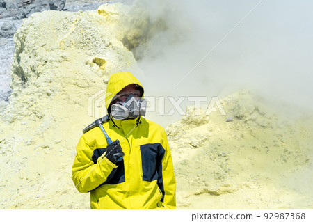 male volcano scientist with a geological hammer and in a respirator on the slope of a volcano nearby among toxic fumes male volcano scientist with a geological hammer and in a respirator on the slope of a volcano nearby among toxic fumes 92987368