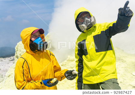 volcanologists on the slope of the volcano collect samples against the backdrop of smoking sulfur fumaroles volcanologists on the slope of the volcano collect samples against the backdrop of smoking sulfur fumaroles 92987427