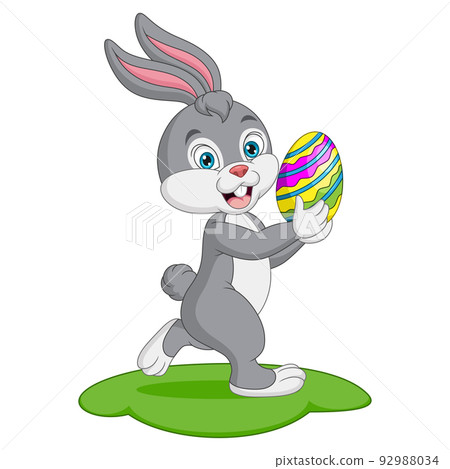 Cute little bunny carrying an easter egg in the grass Cute little bunny carrying an easter egg in the grass 92988034