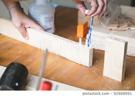 Woodworking operators are using glue to put together the wood parts to assemble and build a wooden table for their customers. Woodworking operators are using glue to put together the wood parts to assemble and build a wooden table for their customers. 92988091