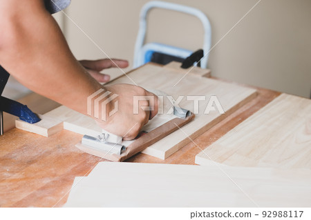 Woodworking entrepreneurs are using sandpaper to decorate wooden pieces to assemble and build wooden tables for their clients 92988117