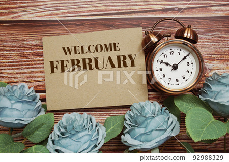 Welcome February written on paper card and rose flower bouquet on wooden background 92988329
