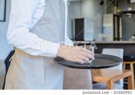 Image cut of a male clerk carrying water at a restaurant Image cut of a male clerk carrying water at a restaurant 92988993