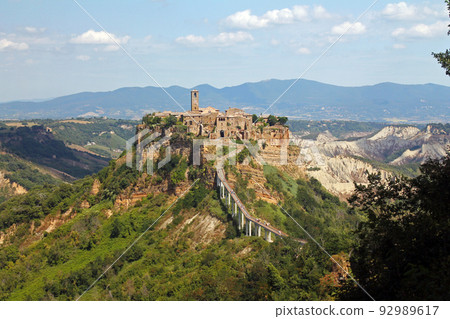 The historical civita village of Bagnoregio standing on a cliff with the long pedestrian bridge 92989617