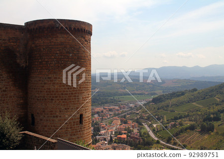 Stone tower and green hills with rooftops near Orvieto 92989751