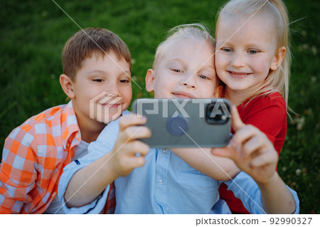 cute funny children shooting selfie with smartphone cute funny children shooting selfie with smartphone 92990327