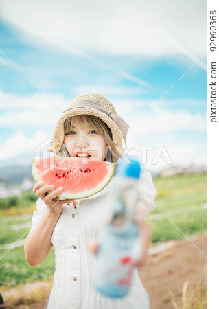 A woman enjoying summer with watermelon and soda pop under the blue sky 92990368