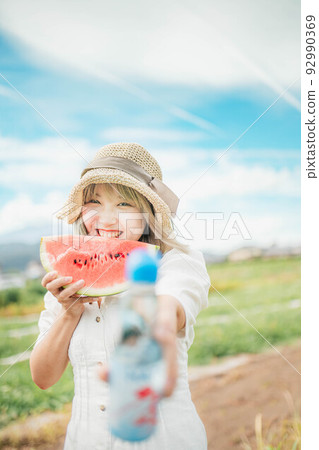 A woman enjoying summer with watermelon and soda pop under the blue sky 92990369