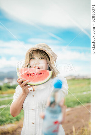 一個女人在藍天下用西瓜和汽水享受夏天 92990371