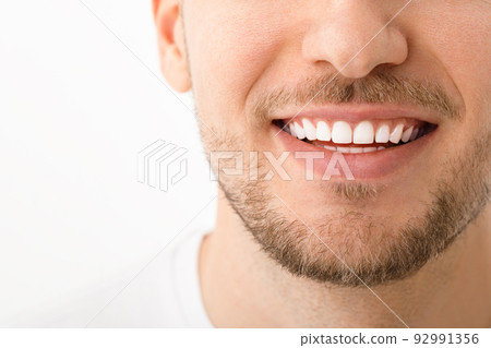A beautiful man is smiling. a smile with white teeth. Close up image. White background with copyspace. A beautiful man is smiling. a smile with white teeth. Close up image. White background with copyspace. 92991356
