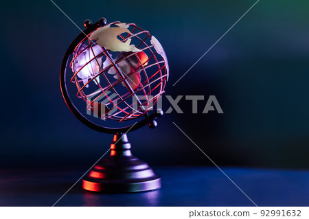Metallic model of a globe with map in blue and red neon light. Bipolarity of the world. Geography concept. Selective focus, Copy space. 92991632