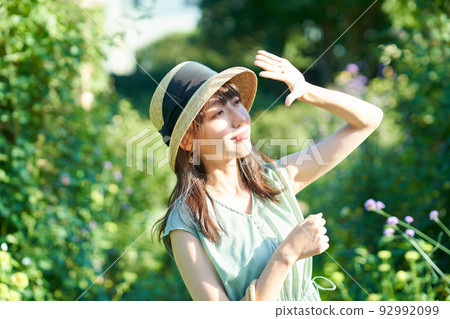 A woman blocking the strong sunlight with her hand 92992099