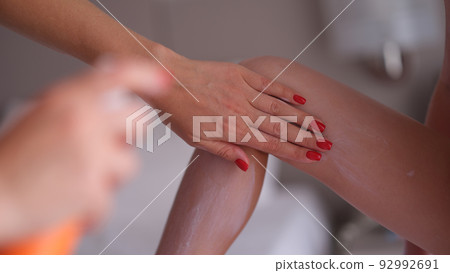 Mom applies sunscreen spray on daughter legs closeup Mom applies sunscreen spray on daughter legs closeup 92992691