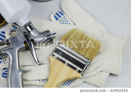 Gloves and a spray gun with a brush, at work at the workplace in the workshop 92992816