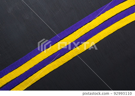 yellow and purple shoelaces, lakers flag, on black wooden background, leaving space for advertising text 92993110