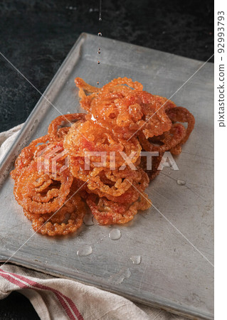 Jalebi Indian sweets on a metal tray on a dark background Jalebi Indian sweets on a metal tray on a dark background 92993793