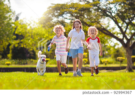 Kids play with dog. Children and puppy run in park 92994367
