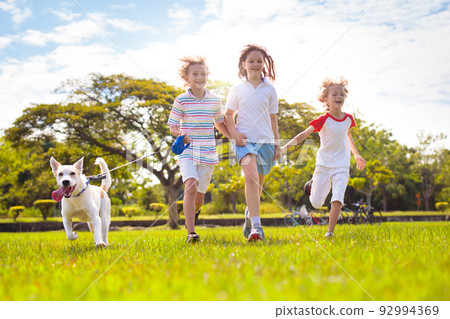 Kids play with dog. Children and puppy run in park Kids play with dog. Children and puppy run in park 92994369
