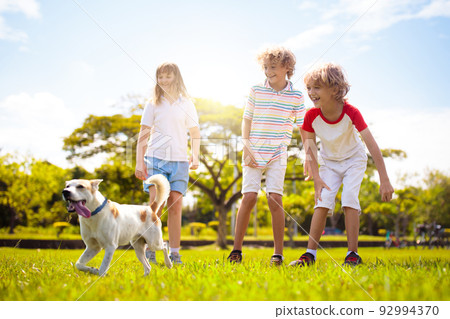 Kids play with dog. Children and puppy run in park Kids play with dog. Children and puppy run in park 92994370