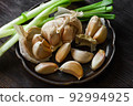 Garlic cloves with scallion on dark ceramic plate. 92994925