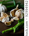 Garlic cloves in composition with scallion on a dark background. 92994942