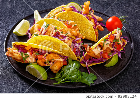 Bang Bang Shrimp Tacos on black plate with sauce 92995124