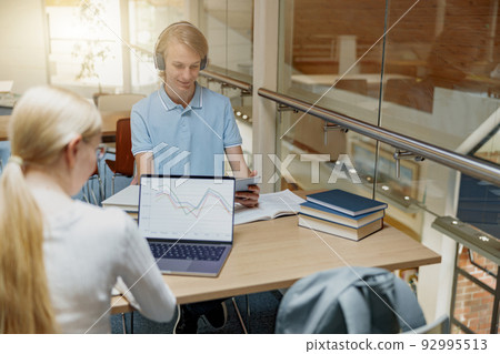 Two friends students with laptop and books studying in University Library Two friends students with laptop and books studying in University Library 92995513