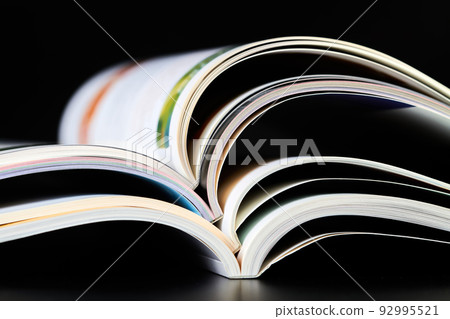 A part of a stack of open magazines on dark background 92995521