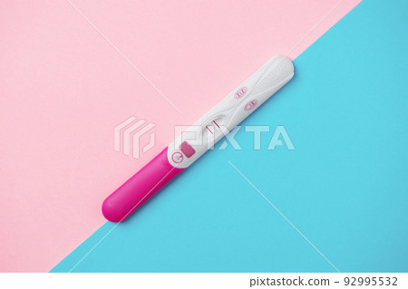 Positive pregnancy test on pink and blue background. Positive result of pregnancy test. Guessing unborn baby gender. Positive pregnancy test on pink and blue background. Positive result of pregnancy test. Guessing unborn baby gender. 92995532