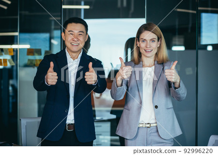 Team of successful managers, group of Asian man and woman, in business clothes looking at camera and smiling holding thumbs up gesture 92996220