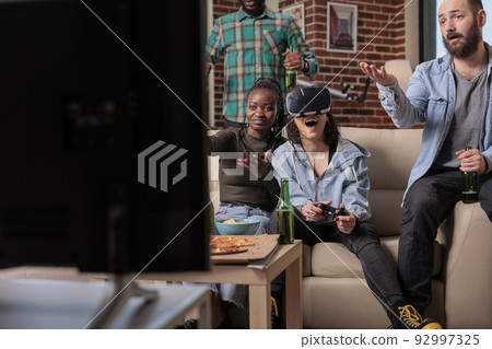 People playing video games with vr glasses at fun gathering, enjoying competition play with 3d headset simulation and virtual reality. Friends cheering to win game on tv console. People playing video games with vr glasses at fun gathering, enjoying competition play with 3d headset simulation and virtual reality. Friends cheering to win game on tv console. 92997325