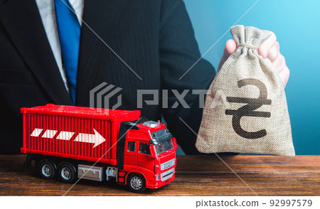 Businessman with ukrainian hryvnia money bag and truck. Income of the transport business and transport of goods. High salaries for drivers. Rising prices, global containers shortage crisis. Logistics 92997579