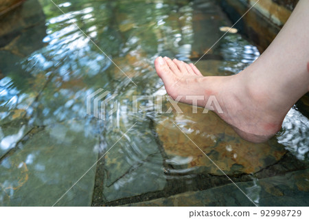 A woman puts her feet in a hot spring 92998729