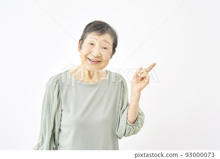 Senior woman pointing to the left with white back Senior woman pointing to the left with white back 93000073