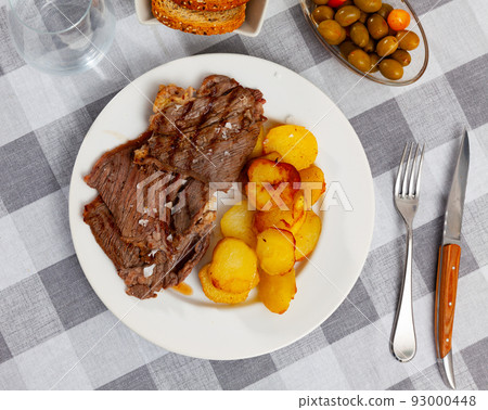 Delicious roasted beef steak with baked potato served with bread and olives 93000448