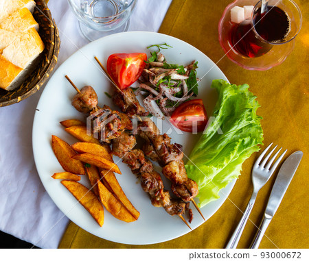 Lamb shish kebab with lettuce, tomatoes and French fries closeup. Turkish cuisine 93000672