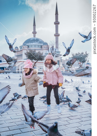 girl playing and chasing pigeons in city square 93002267