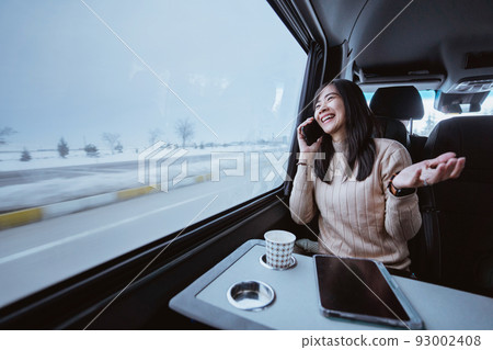 woman making a phone call during her trip inside a van 93002408