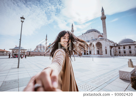 woman holding hand and taking someone to get closer with mosque 93002420