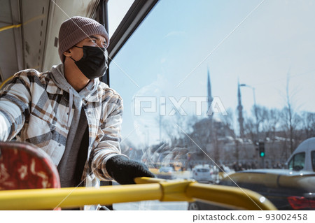 asian man with mask looking through window of a bus asian man with mask looking through window of a bus 93002458