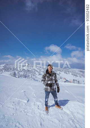 man looking at camera while standing at the top of snowy mountain 93002482