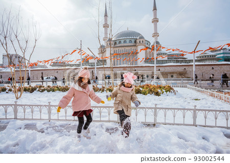 two little girl playing with snow in city square 93002544